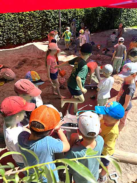Kinder unter dem Sonnensegel spielen mit der Wasseranlage im Sandkasten