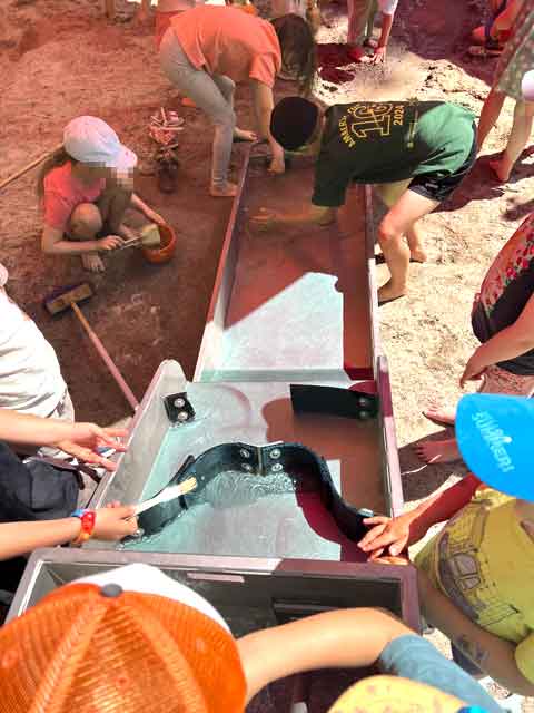 Kinder spielen bei heißem Wetter gerne mit der Wasseranlage im Sandkasten