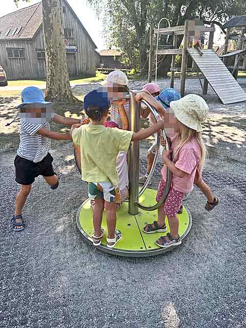 Kinder sind fröhlich an einem Spielgerät beim Spielplatzbesuch