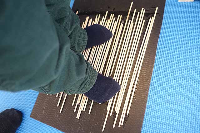 KInd steht barfuß auf Mikadohölzchen