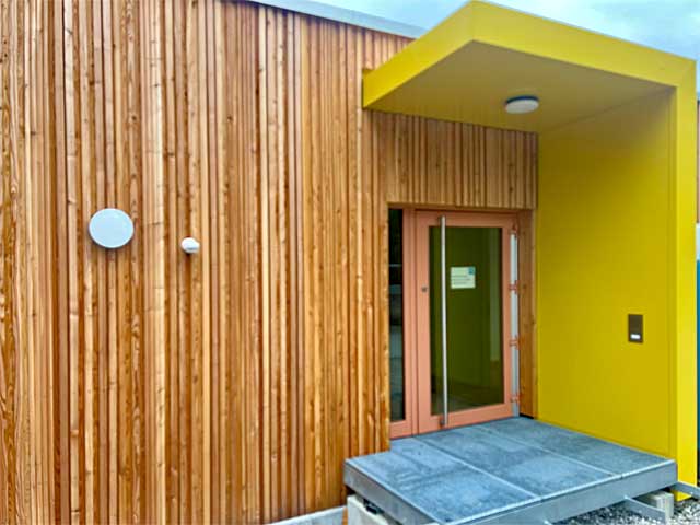 Eingangsbereich zur neuen Holzmodulanlage des Kinderhauses Riederau mit gelbem Vorbau