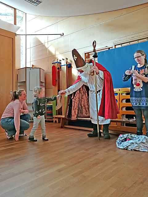 Der Nikolaus besucht die Mondgruppe und übergibt einem Kind ein Geschenksäckchen.