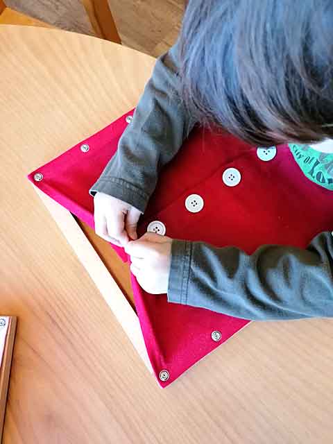 Ein Kind übt an einem Modell das Knöpfen