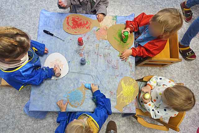 Fünf Kinder sitzen um den Tisch und malen mit Deorollern