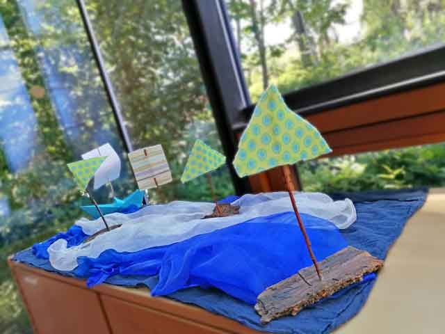 Boote aus Baumrinde schwimmen auf blauen Tüchern