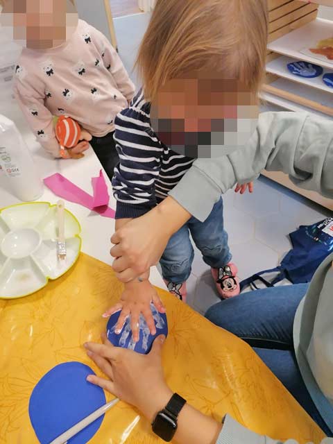 Ein Kind macht einen Handabdruck für seine Schneekugel