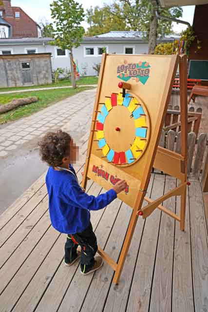 Ein Kind steht vor einem sich drehenden Glücksrad