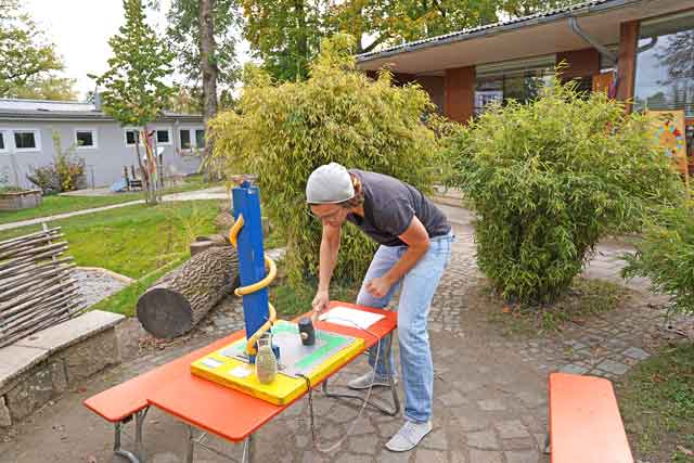 Ein Erwachsener steht an der Spielestation "Hau die Erbse"