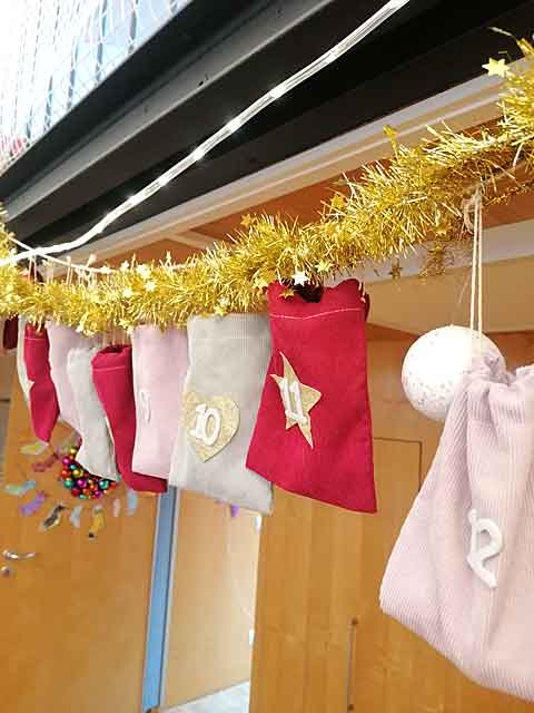 Verschiedenfarbige Säckchen hängen als Adventskalender an einer Schnur im Gruppenraum