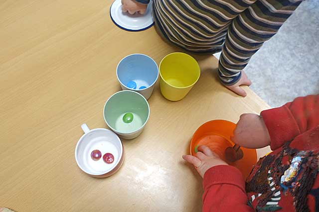 Kinder sortieren bunte Muggelsteine nach Farben