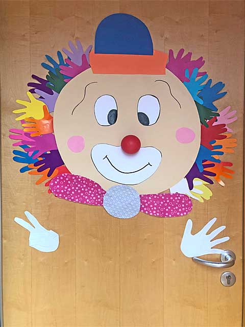 Ein buntes Clowngesicht aus Papier hängt an der Gruppentür