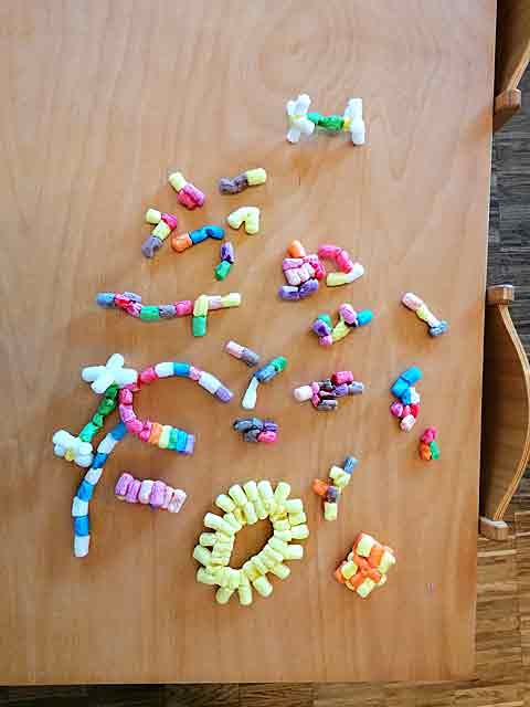 Figuren aus buntem PlayMais liegen auf dem Tisch